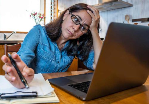 vrouw zuchtend achter laptop