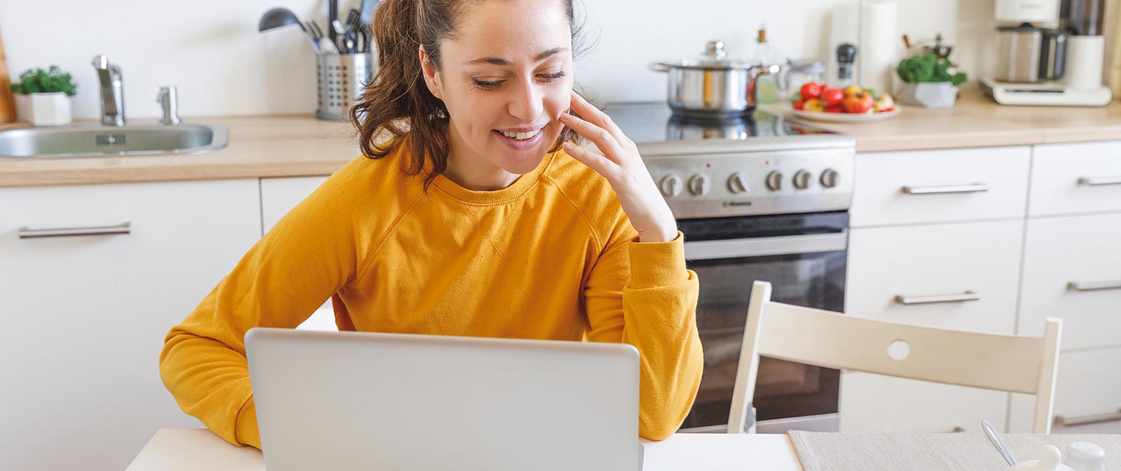 Photo d'une femme utilisant son ordinateur portable dans sa cuisine