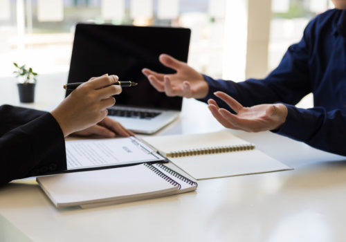 Hommes qui discutent d'une assurance perte d'emploi lors de la signature d'un crédit à la consommation